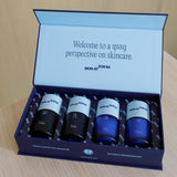 An open Skin at Peace gift box on a wood table with the four bottles inside: Clean, Tone, Day, and Night.