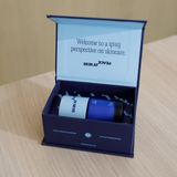 A small open Skin at Peace gift box on a wood table holding two bottles.