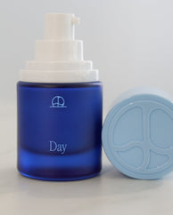 Day, vitamin C serum + moisturizer, with its cap off.