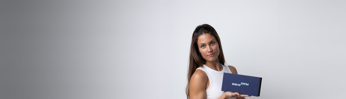 A woman in a white top holding the Skin At Peace box.
